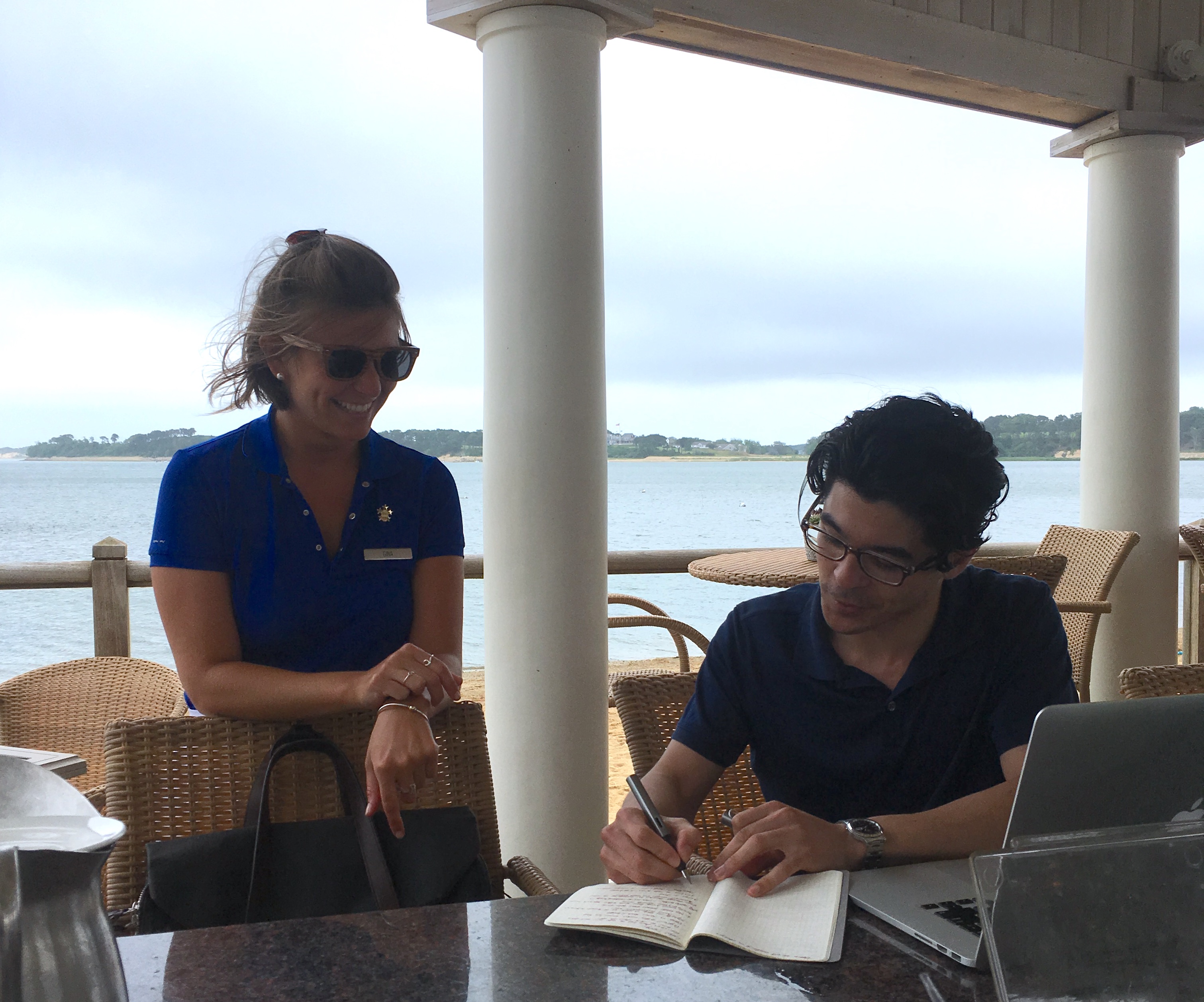 Researcher taking notes with staff member on resort terrace
